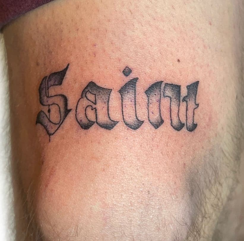 Blackletter word Saint in heavy gothic script on a thigh