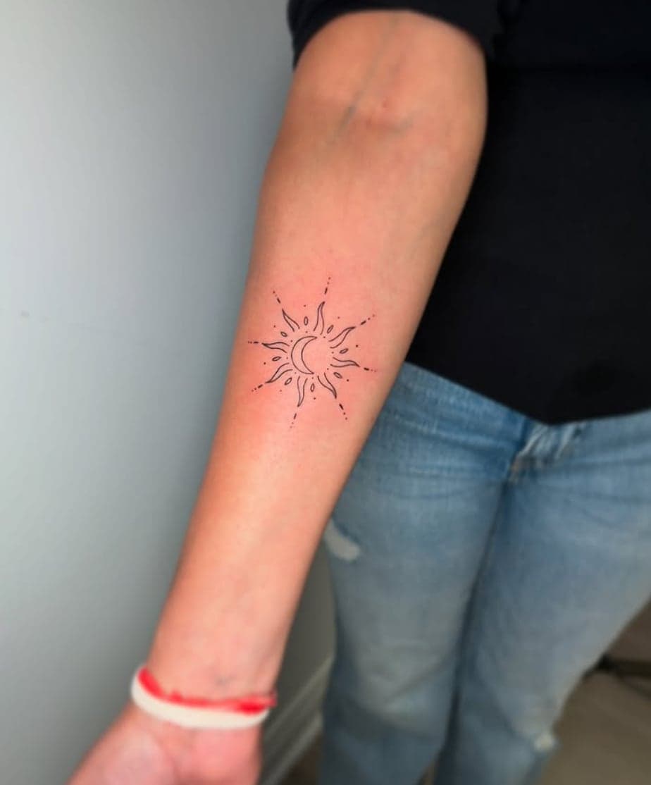 Delicate dotwork sun and crescent moon ornament on a forearm