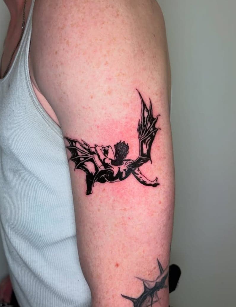 Solid black fairy silhouette with sharp wings on an upper arm