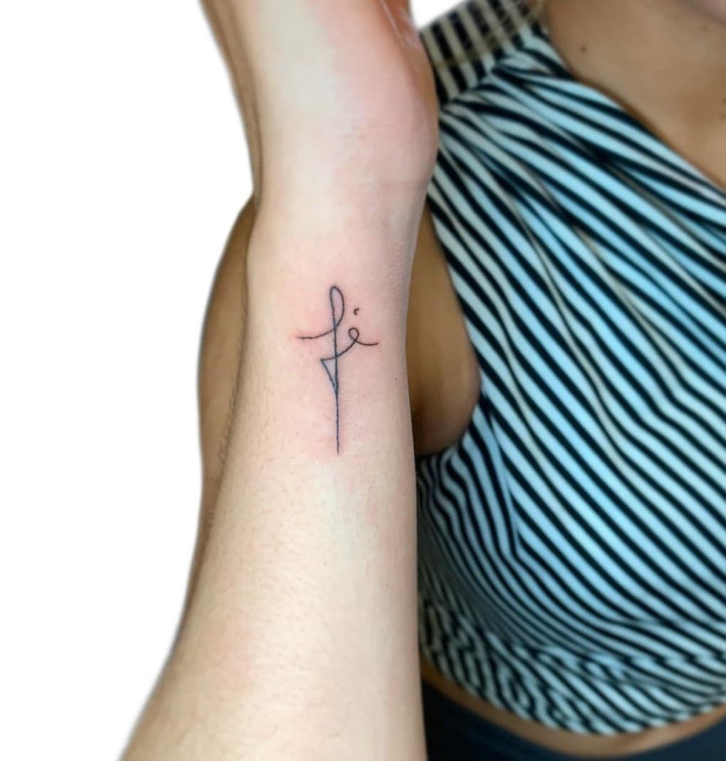 Fine script word fé forming a cross on a forearm