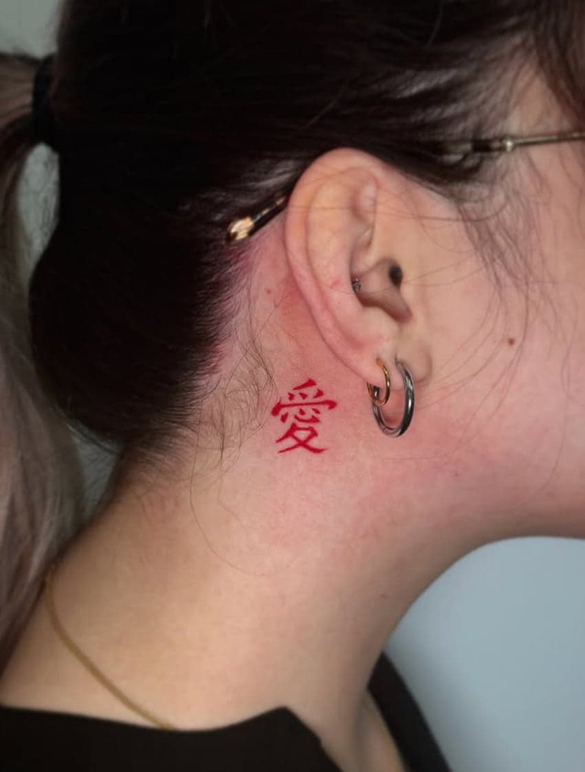 Red kanji for love tattooed behind an ear