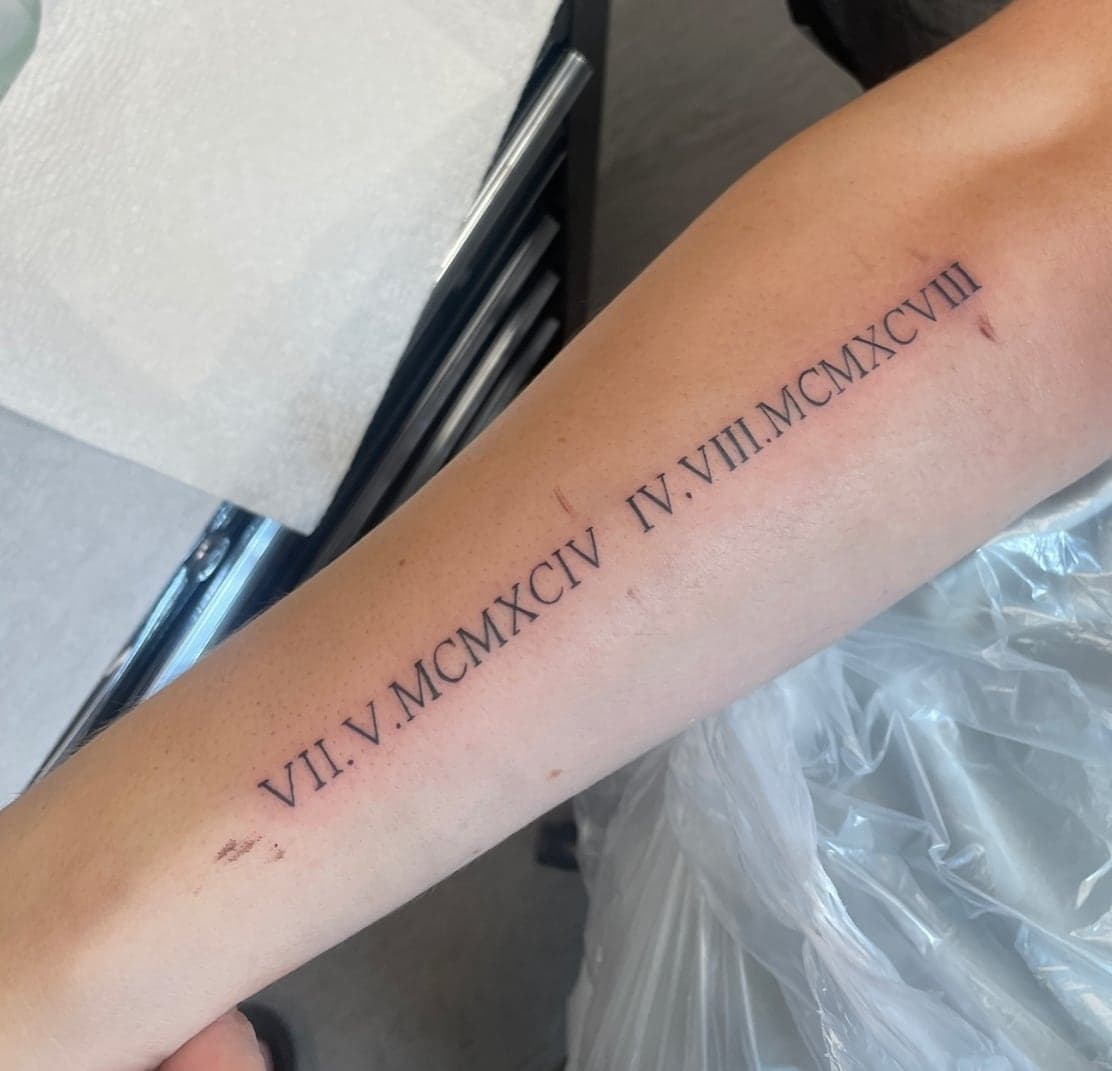 Two dates in fine Roman numerals along the inside of a forearm