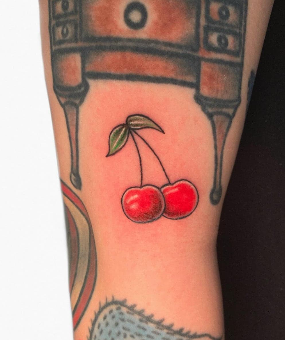 Traditional-style red cherries with a green leaf on an arm