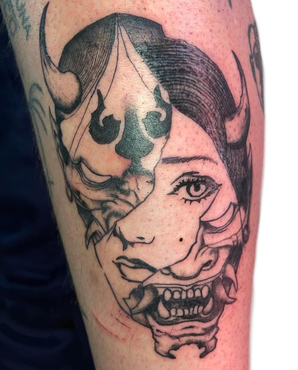 Black-and-grey split face of a hannya mask and a woman's face, on a calf